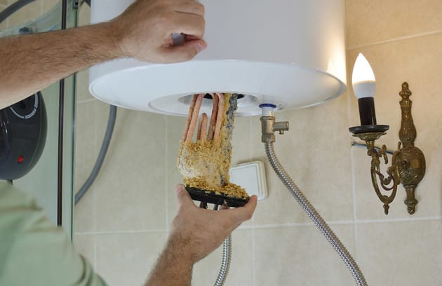Technician removing mineral buildup from a water heater in Danville